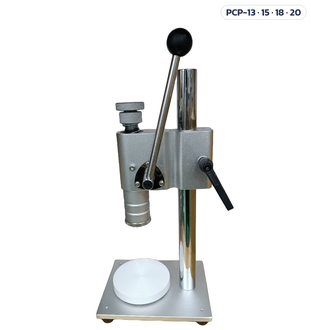 เครื่องย้ำปลอกฝา/กดหัวสเปรย์น้ำหอม มือโยก PCP-13 / 15 / 18 / 20 – ภาพถ่ายเครื่องแบบแท่นวางสีขาว โครงสร้างเหมือนแบบแท่นวางสีดำ: เสาโครเมียม ตัวเรือนสีเงิน คันโยกปลายลูกดำ หัวกดใต้ตัวเรือน (แท่นวางมีทั้งสีดำและสีขาว)